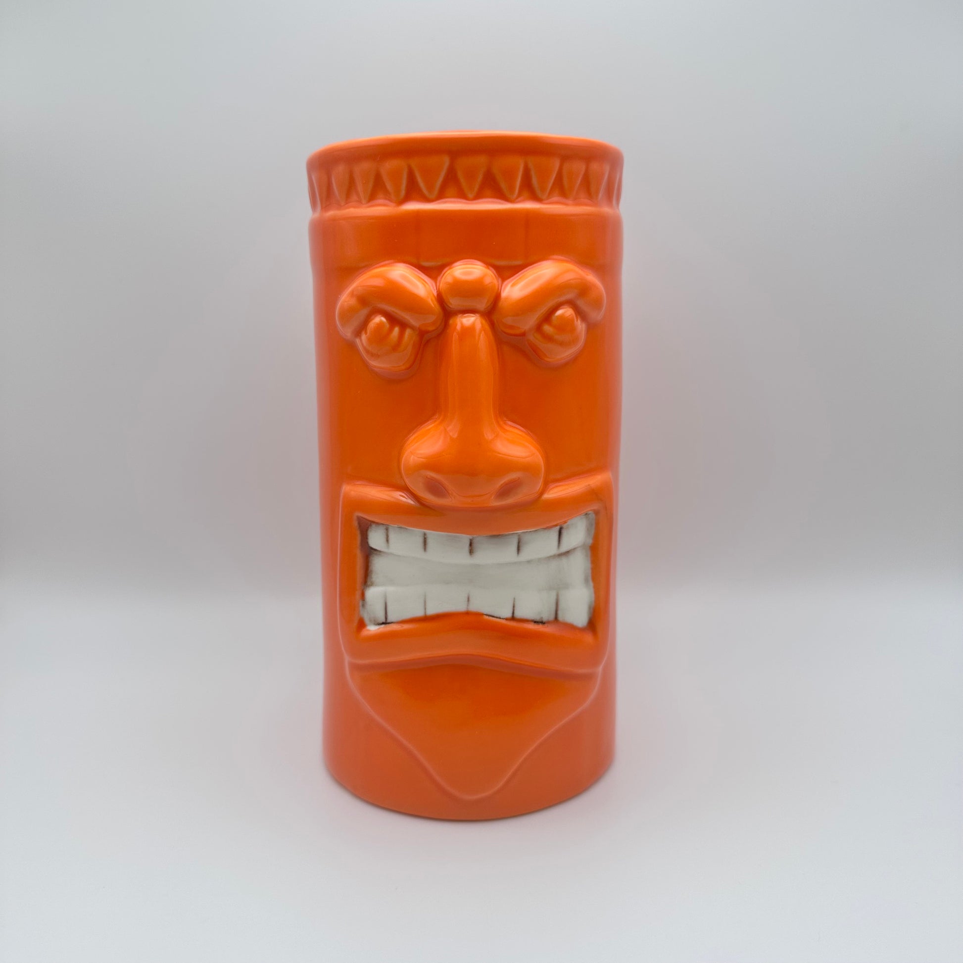 Orange ceramic mug with a face design on a white background