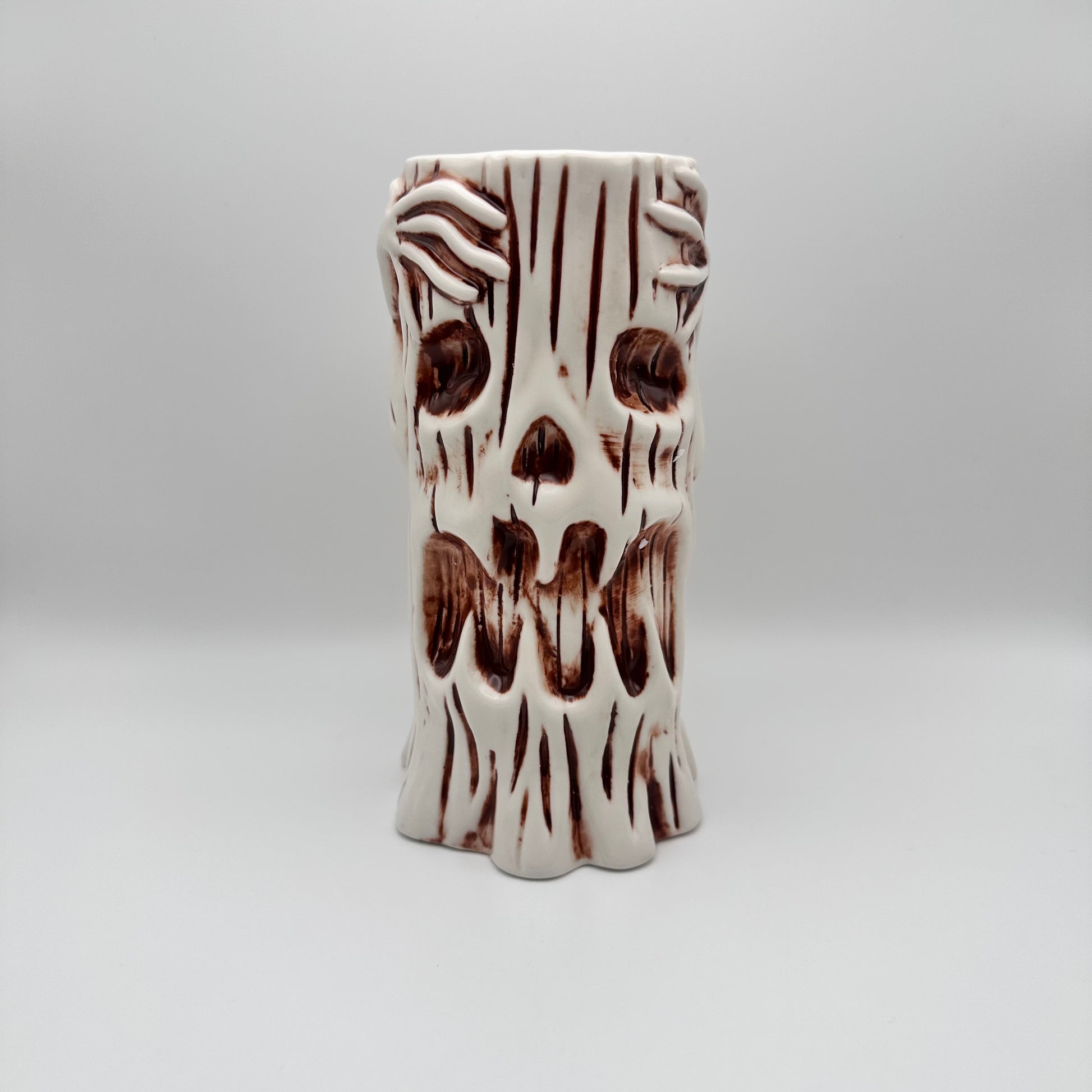 Cylindrical ceramic vase with brown abstract patterns on a white background