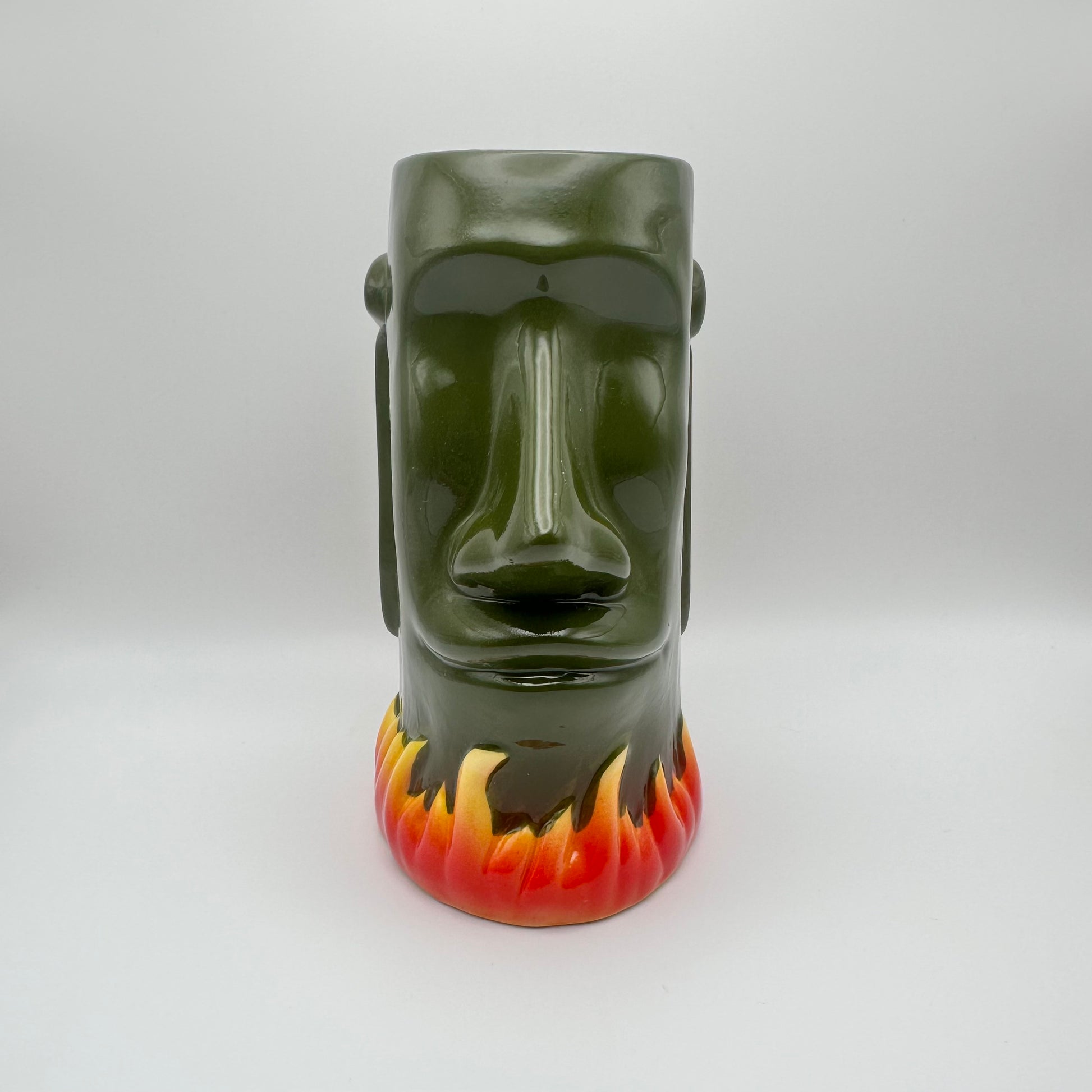 Green ceramic mug shaped like a face with flame design on a white background