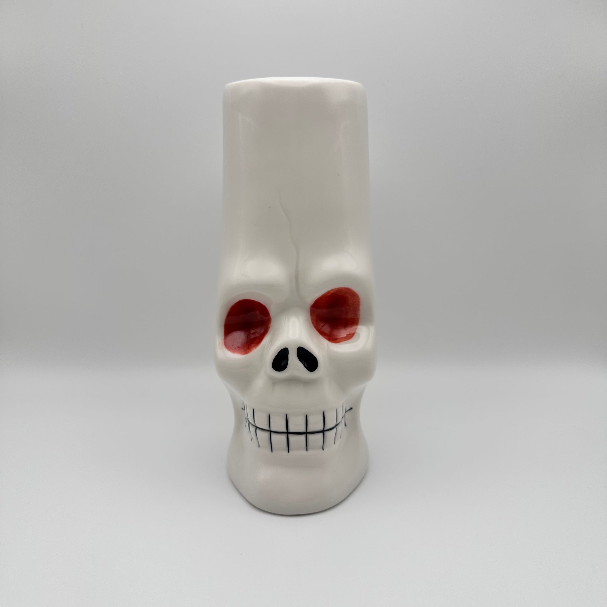 Skull-shaped mug with red eyes and a white background