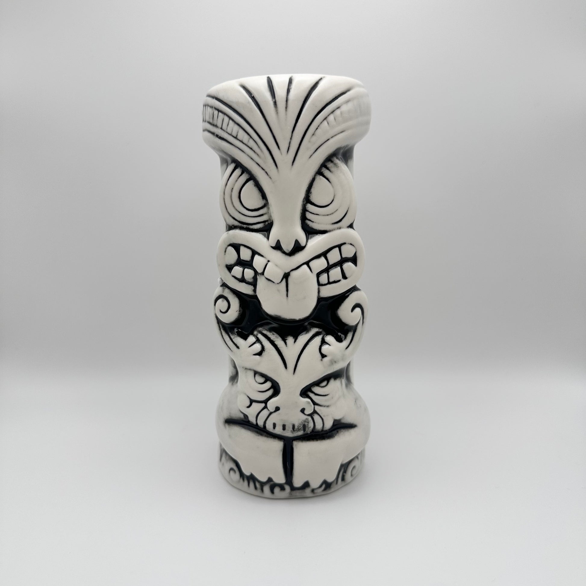 Black and white tiki mug with tribal design on a gray background