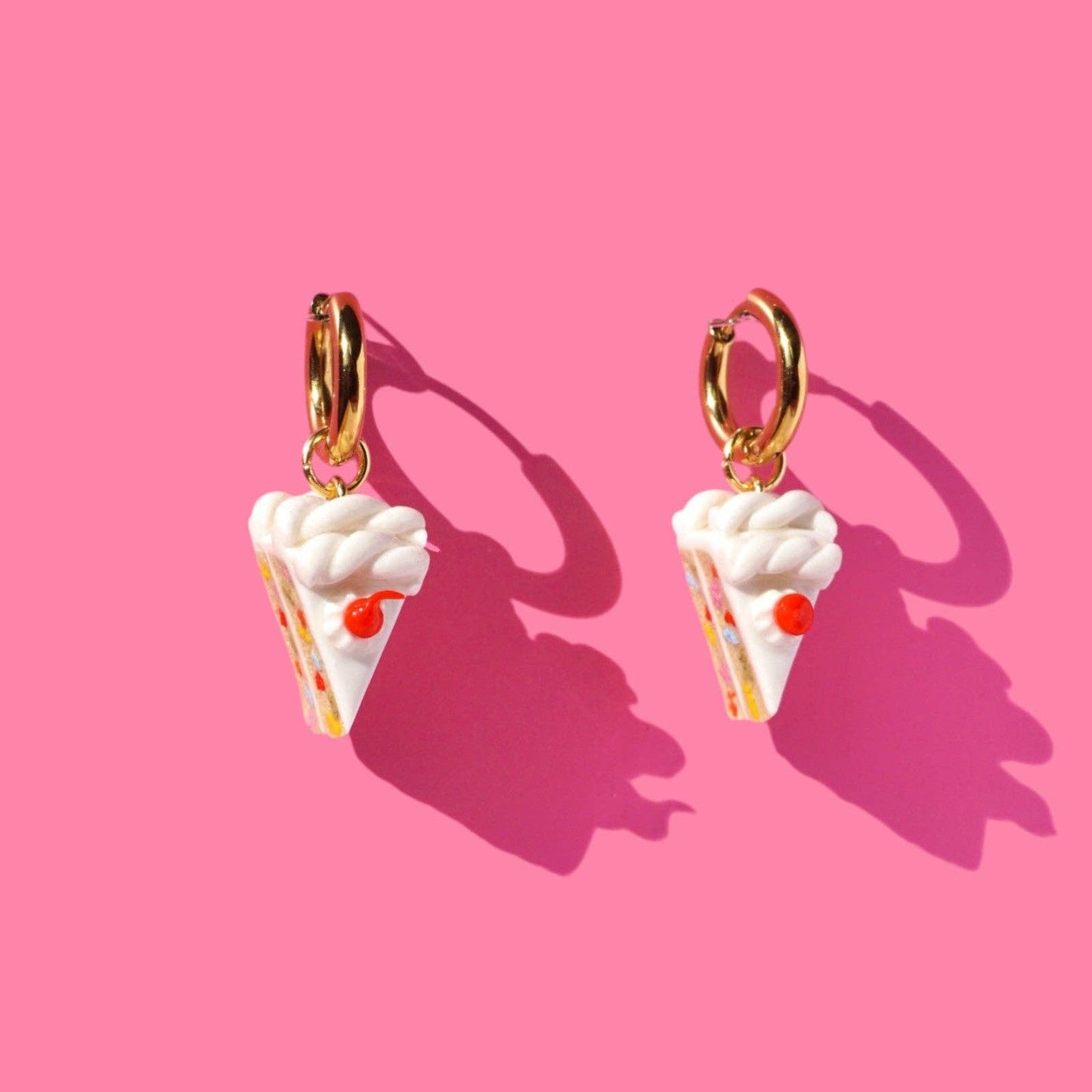 Whilte Cake earrings on a pink background