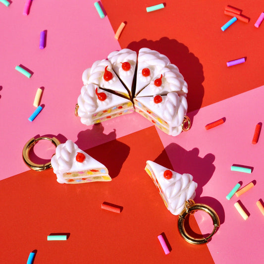 Cake-shaped keychains or earrings on a colorful background with sprinkles