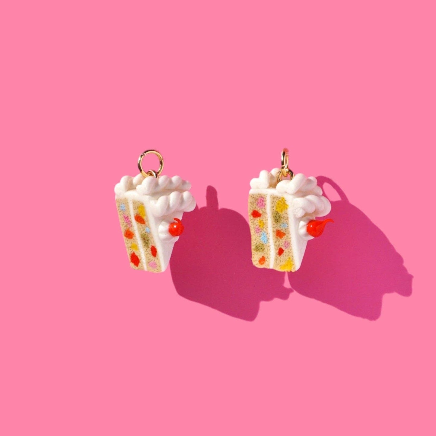 Pair of confetti white cake slice earrings on a pink background