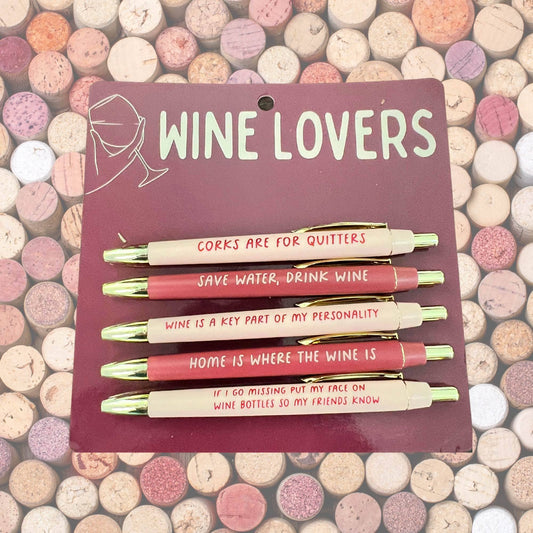 Set of pens with humorous wine-themed sayings on a card labeled 'Wine Lovers' against a colorful background.