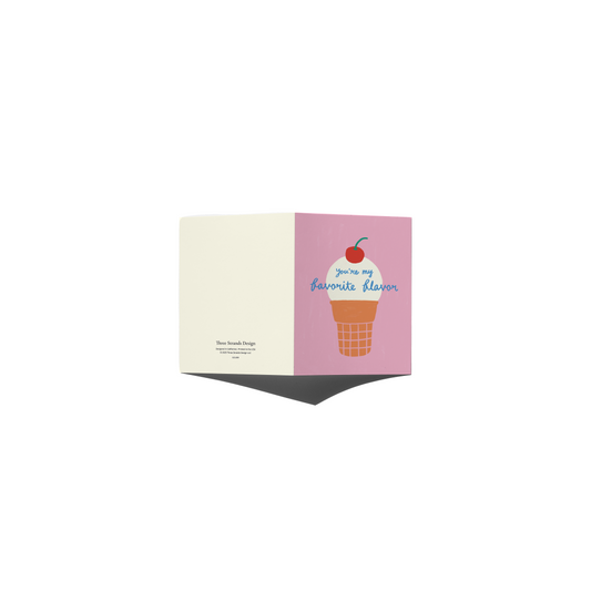 A folded greeting card shown open against a plain white background, with one side in warm cream and the other in dusty pink, both printed with an ice cream cone illustration and the phrase 'You're my favorite flavor.'.