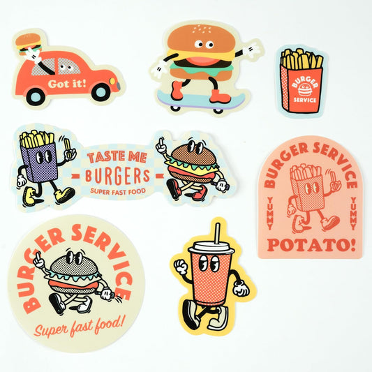 Set of seven colorful fast food-themed stickers featuring different cartoon characterizations of burgers, fries, and a soda. Text on some of the stickers (Example: "Taste Me Burgers - Yummy Fast Food").