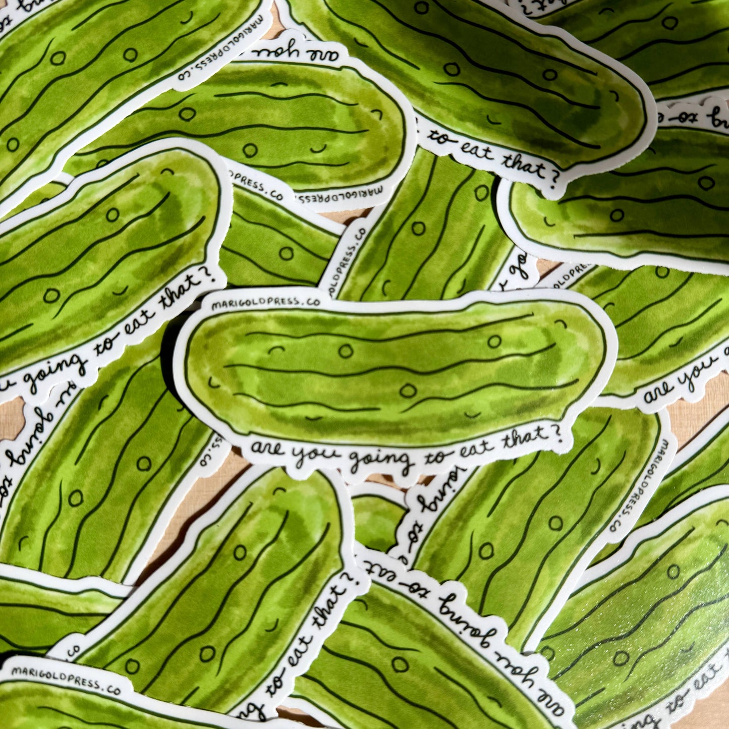 Green pickle-shaped stickers with text "are you going to eat that?" on a beige background