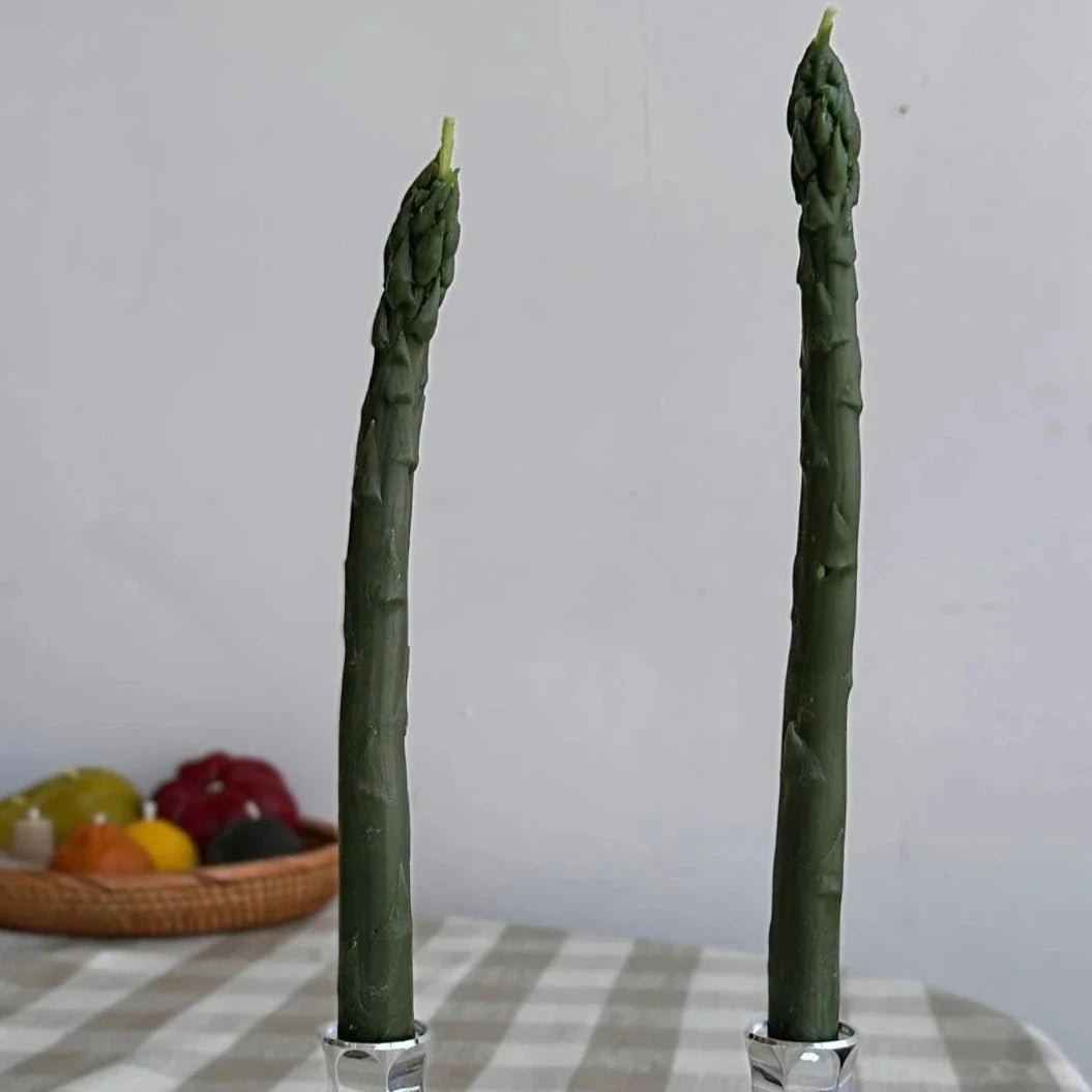 Two green tapered candles that look like stalks of asparagus in silver candle holders