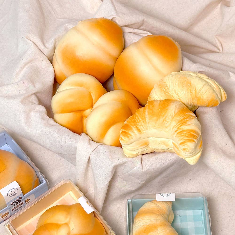 Assorted bread roll stress balls including croissants on a light fabric background