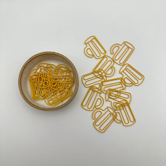 Pile of beer mug paperclips on table and in ramekin