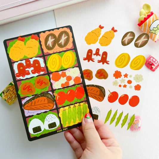 Colorful Japanese food-themed stickers held by a hand on a white background with additional stickers scattered around.