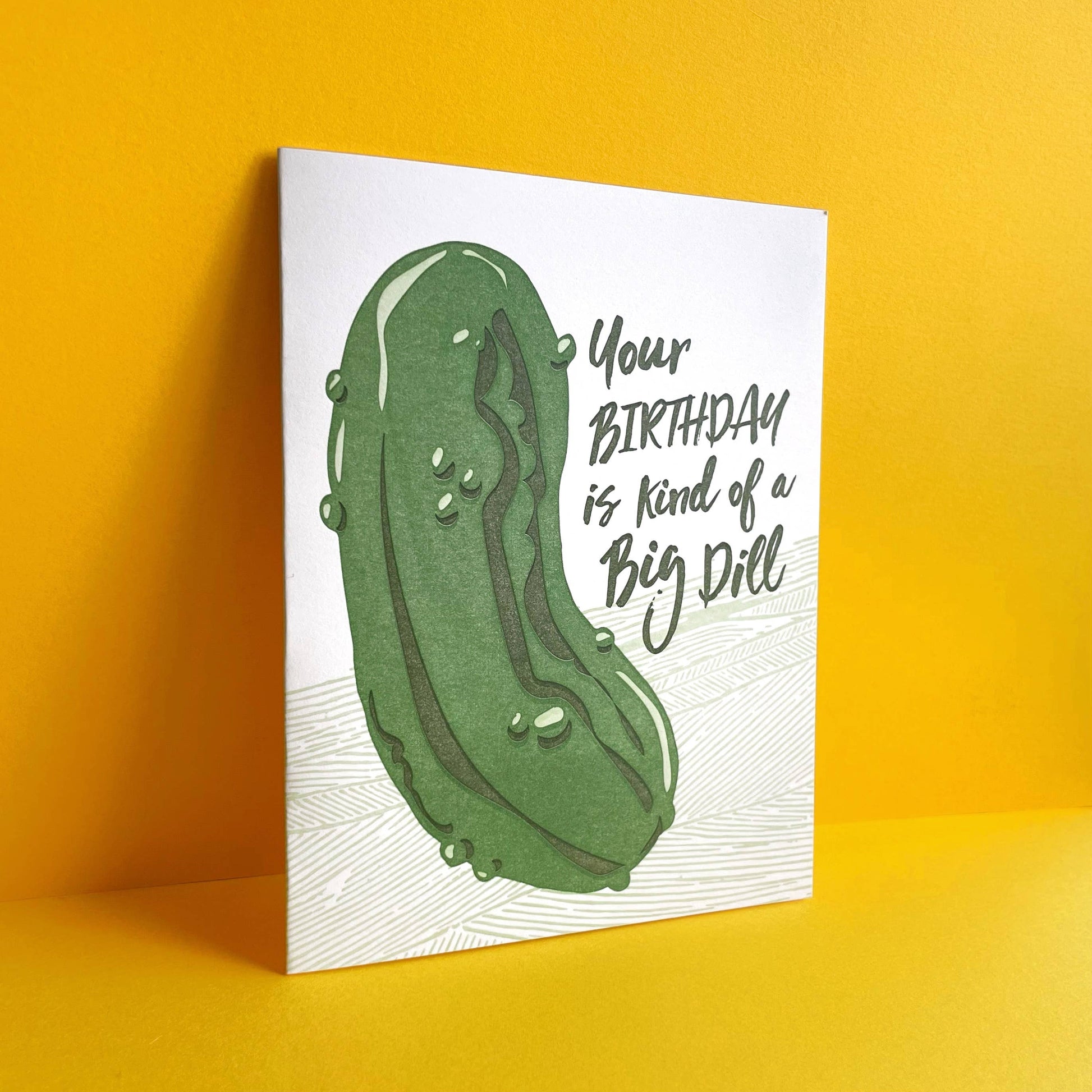 Greeting card with a large dill pickle on it with text that reads "Your birthday is kind of a big dill"