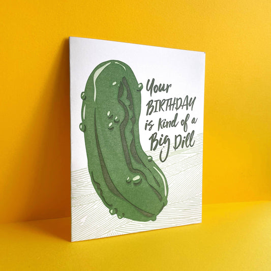 Greeting card with a large dill pickle on it with text that reads "Your birthday is kind of a big dill"