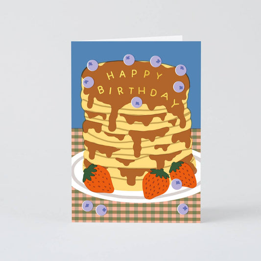 card with a stack of pancakes on it, decorated with blueberries and strawberries and text on top of the syrup that reads "Happy Birthday"