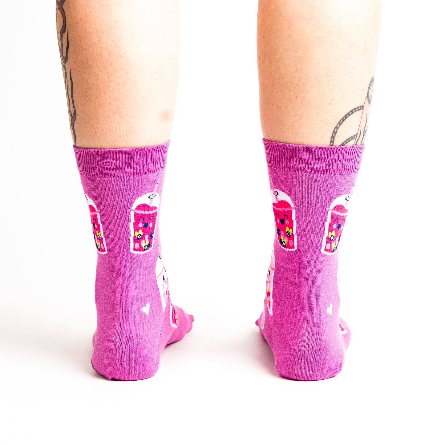 Pink socks with colorful boba bubble tea drink illustrations and heart patterns on a white background