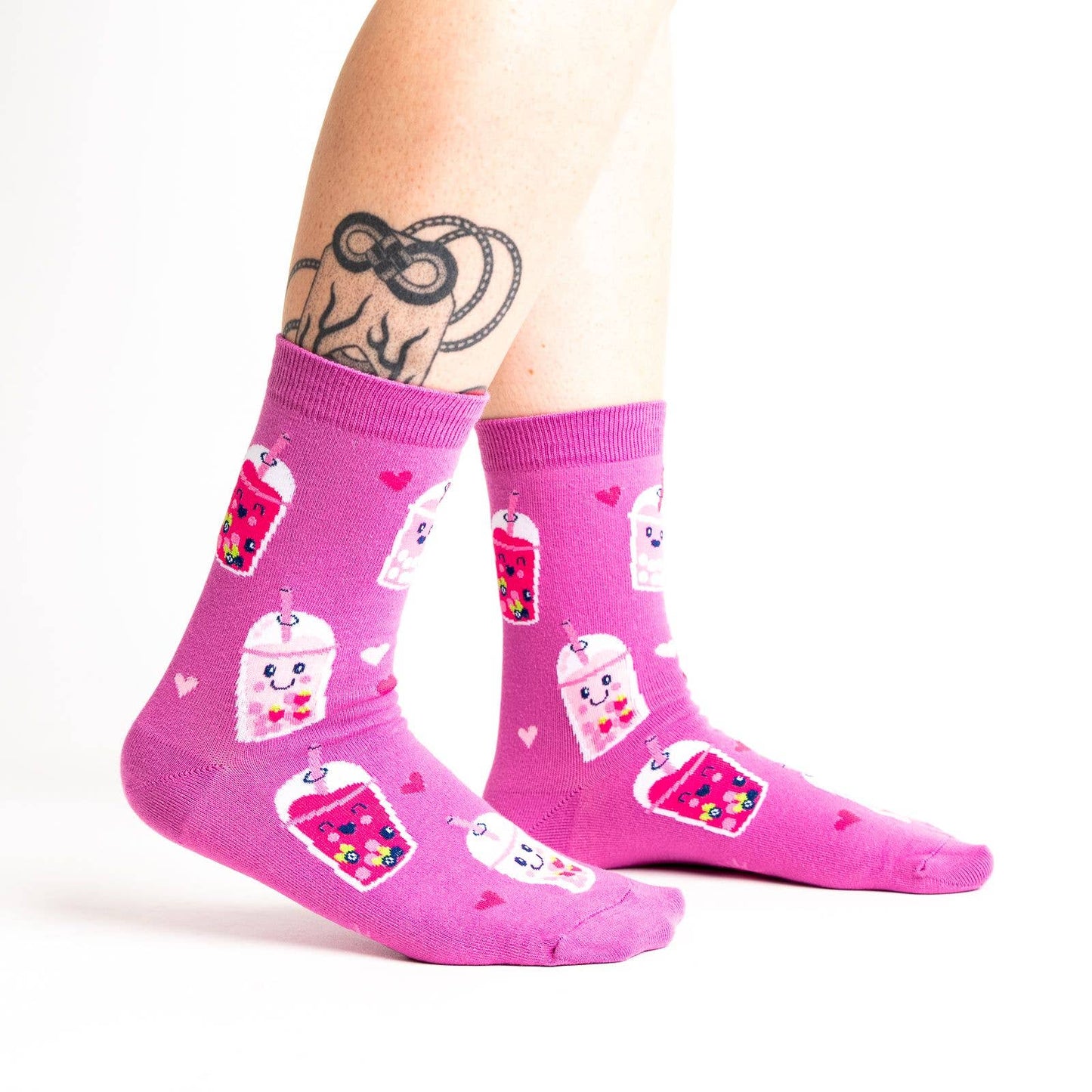 Pink socks with colorful boba bubble tea drink illustrations and heart patterns on a white background