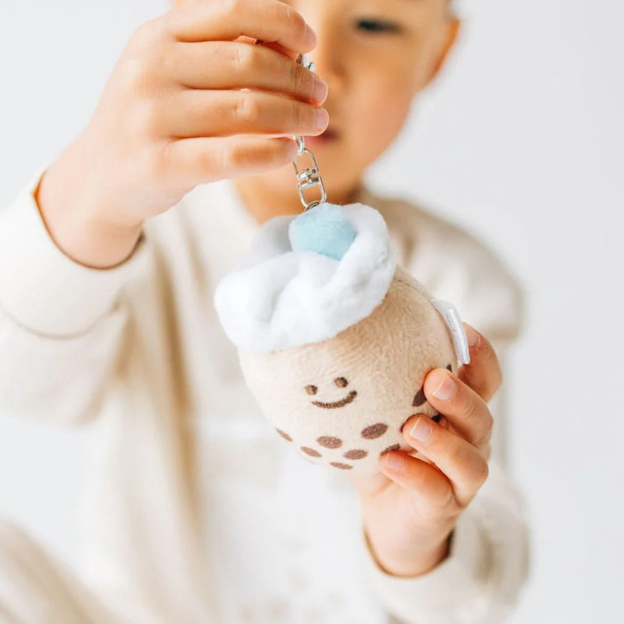 Boba plush keychain with a teal colored straw being held by a child