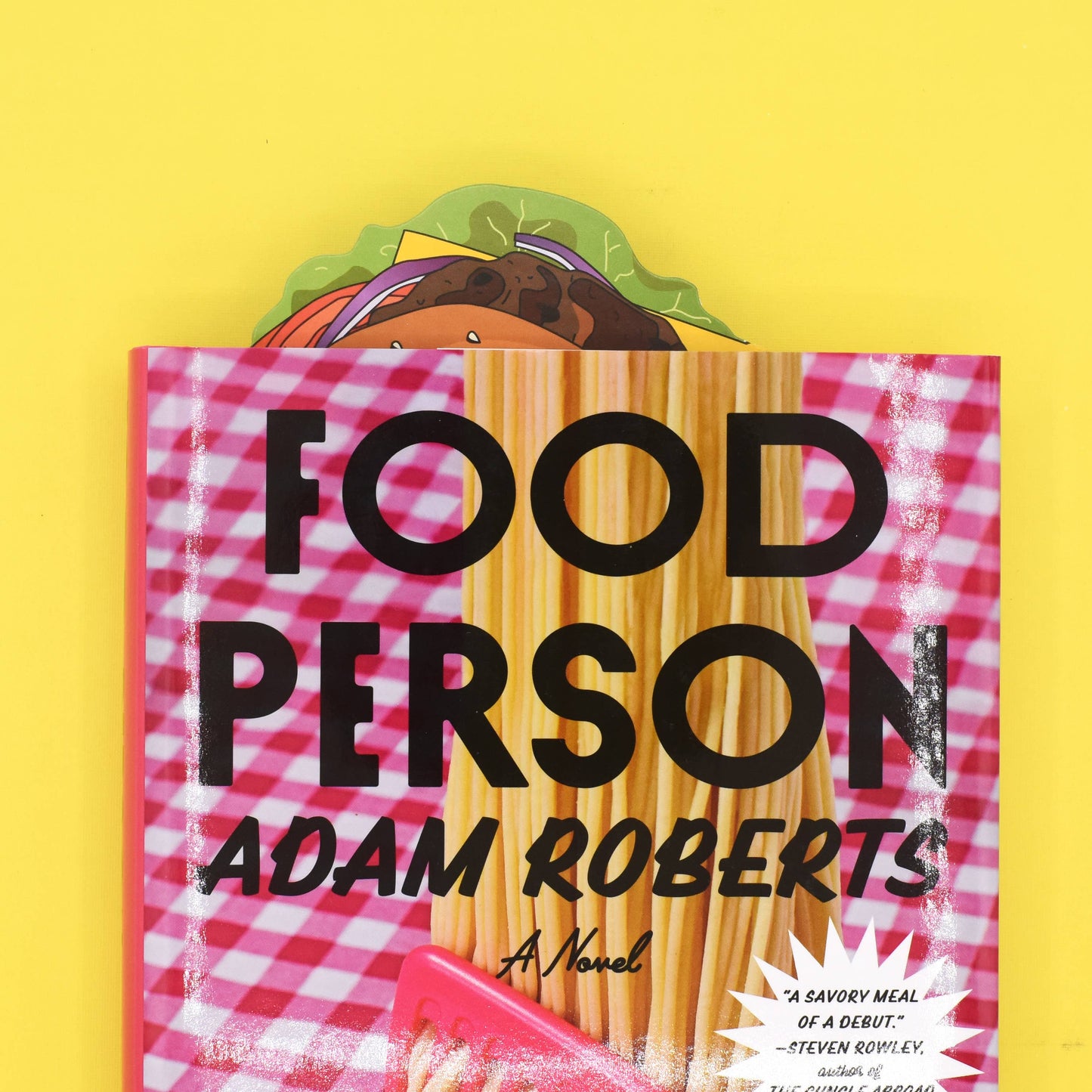 Burger bookmark sticking out of a book titled "Food Person" by Adam Roberts