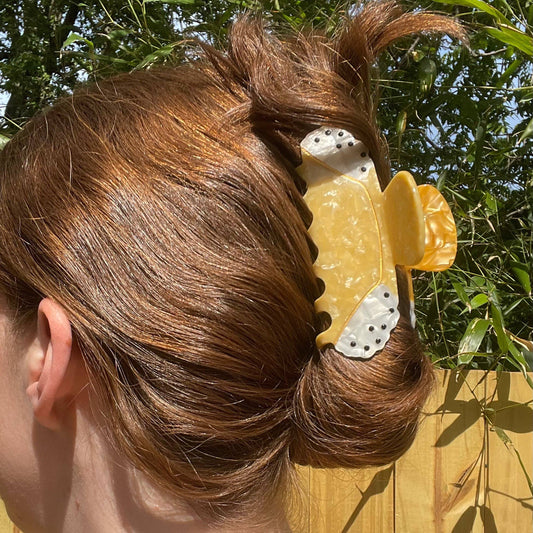 Person with a decorative cannoli shaped hair clip in their hair outdoors