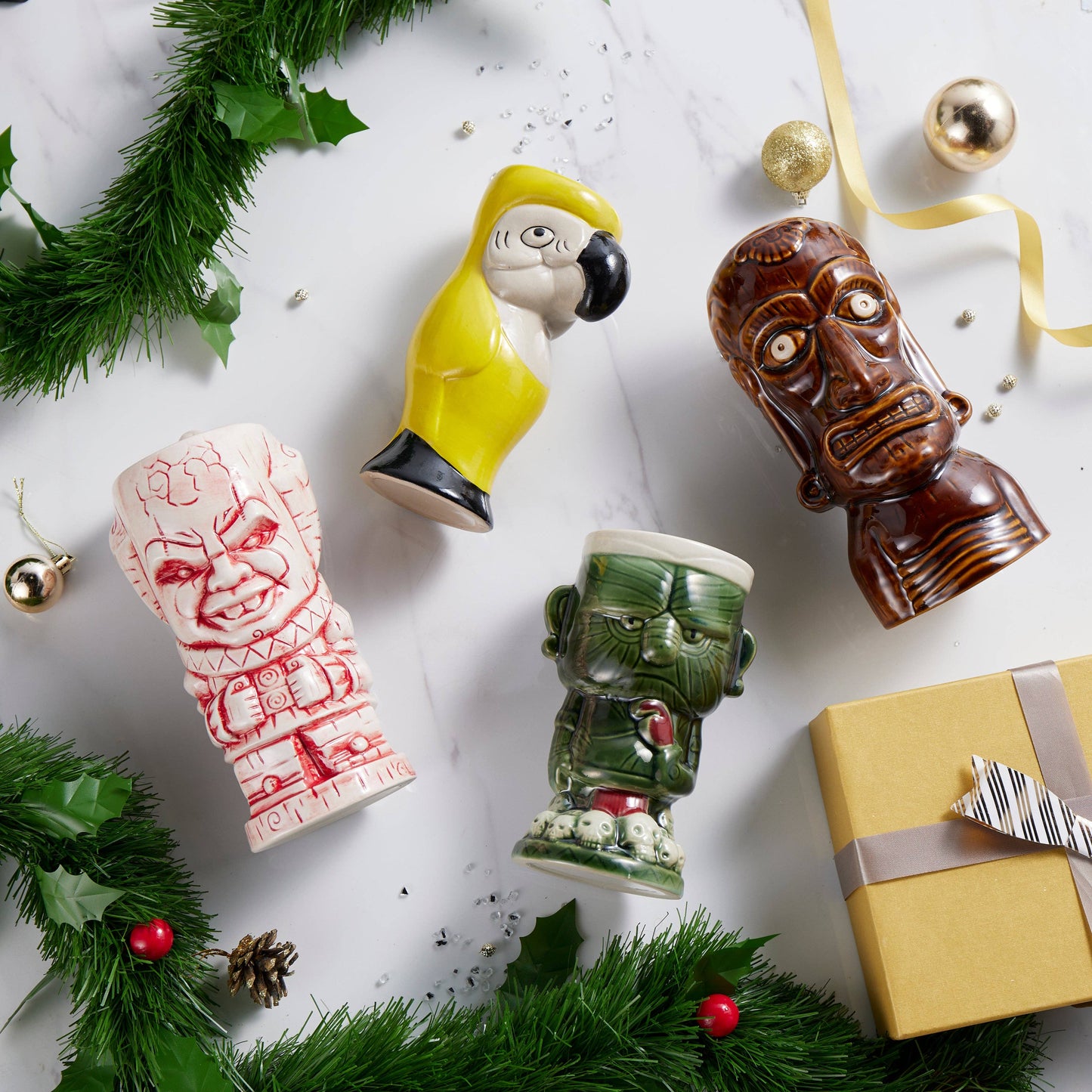 Decorative tiki mugs on a festive background with greenery and a gift box.
