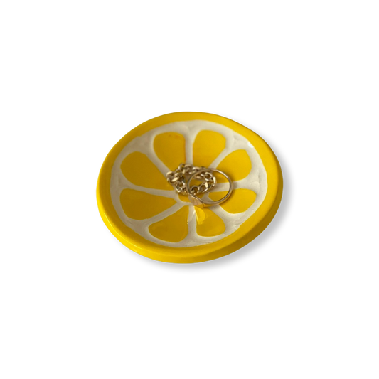 Yellow lemon sliced-shaped dish with a gold ring on a white background