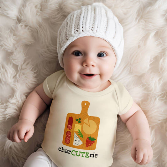 Baby wearing a onesie with a charcuterie design on a fluffy white surface