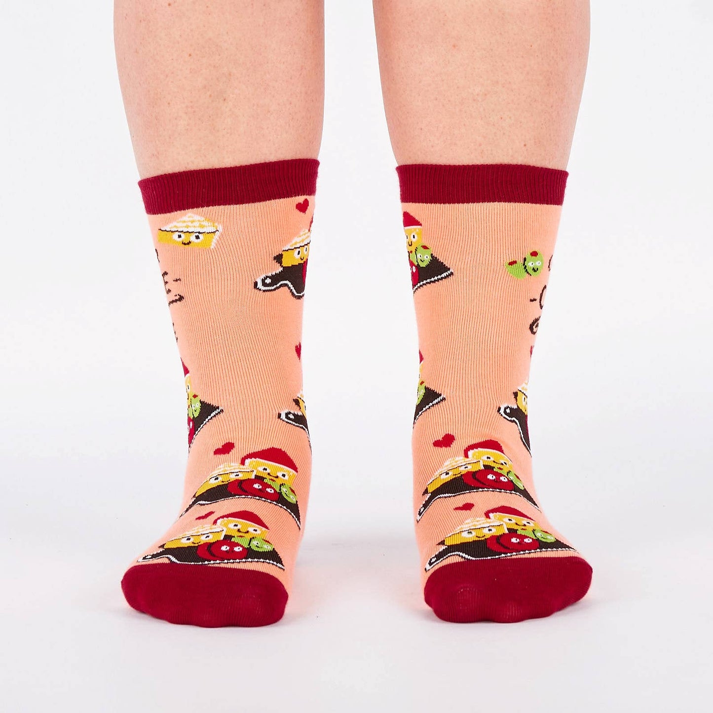 Pair of pink and burgundy socks with cartoon illustration of a charcuterie board design and text (char-CUTE-erie) on a white background