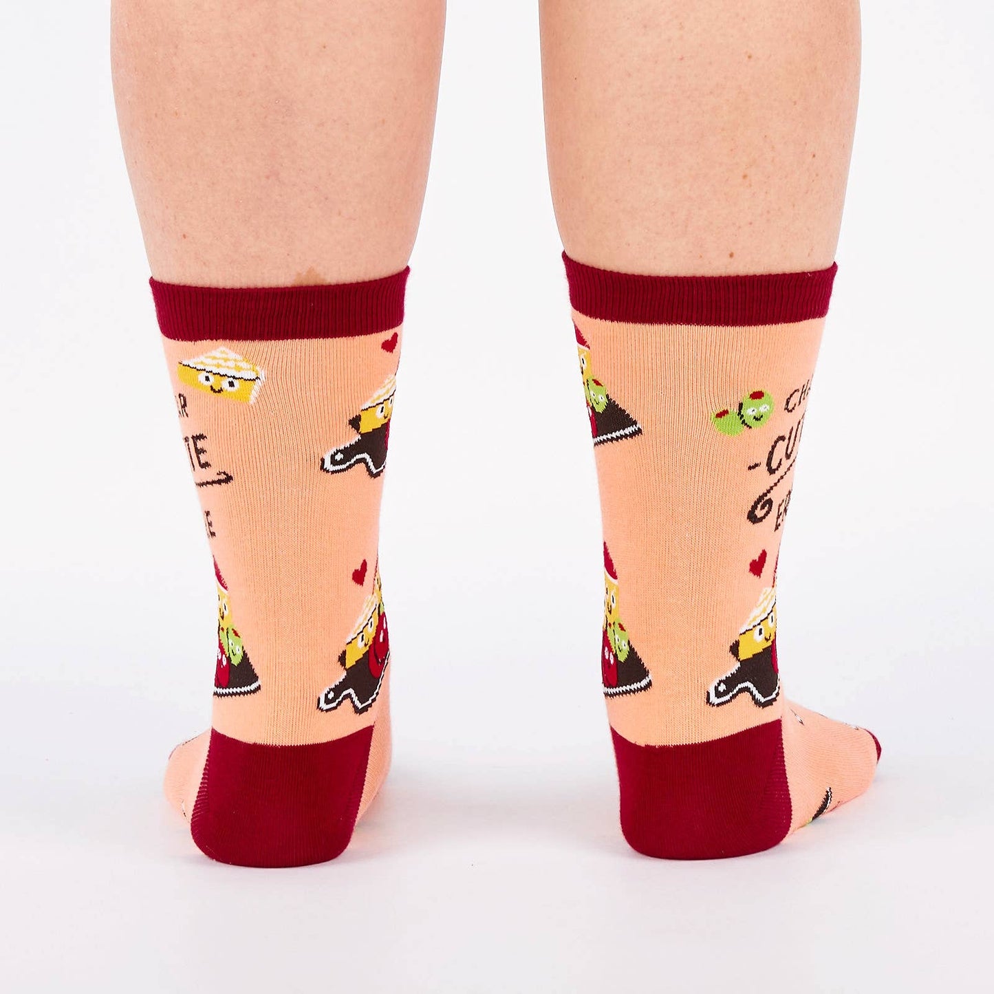 Pair of pink and burgundy socks with cartoon illustration of a charcuterie board design and text (char-CUTE-erie) on a white background