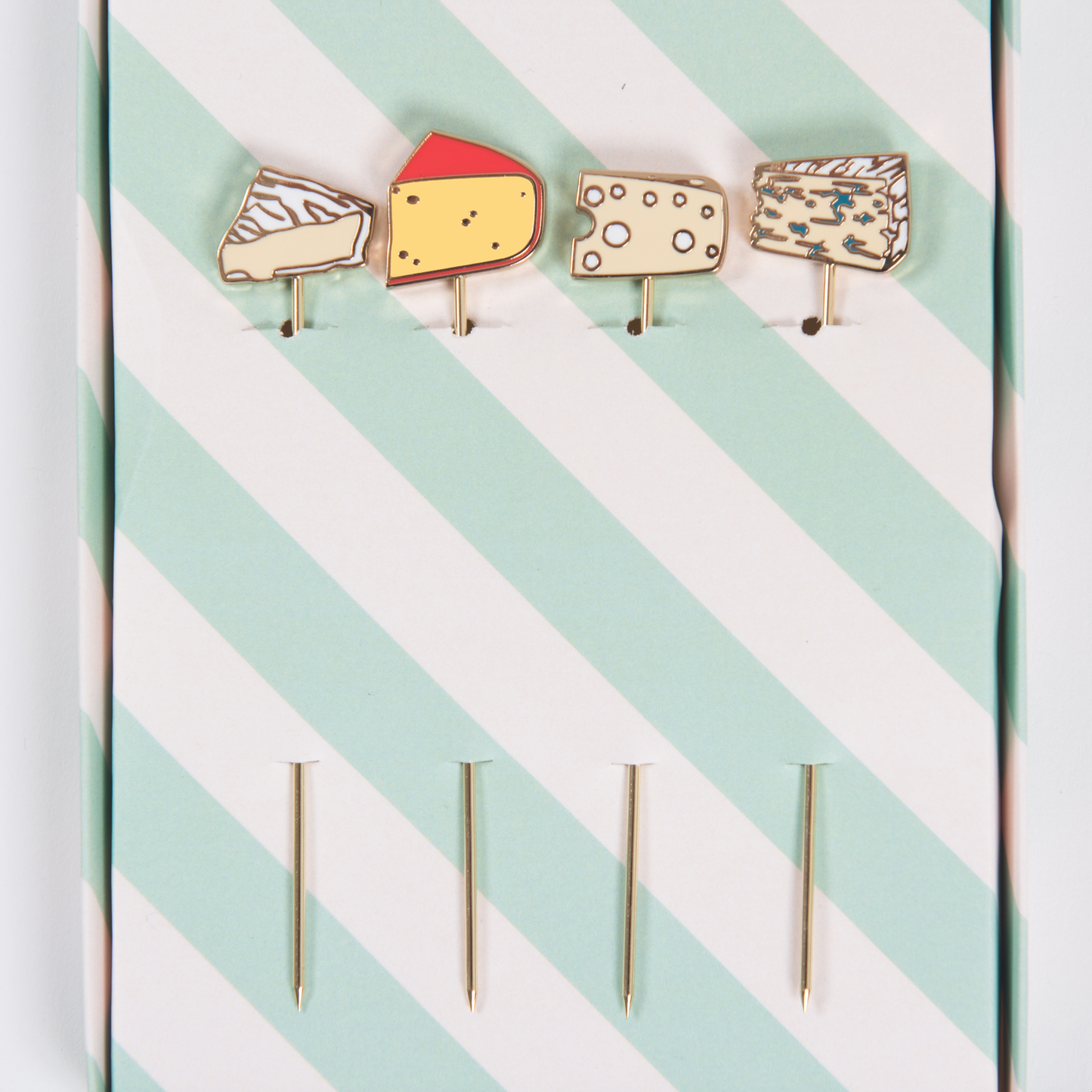 Set of four cheese-themed cocktail picks on a green and white striped background