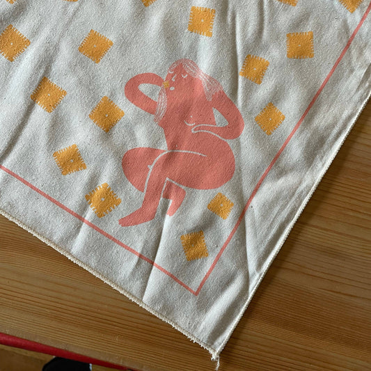 Bandana with a pink nude figure design eating cheez its pictured on a wooden surface