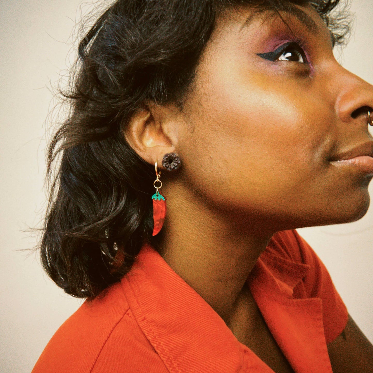 Woman wearing a red top with a neutral background and the chili pepper earrings