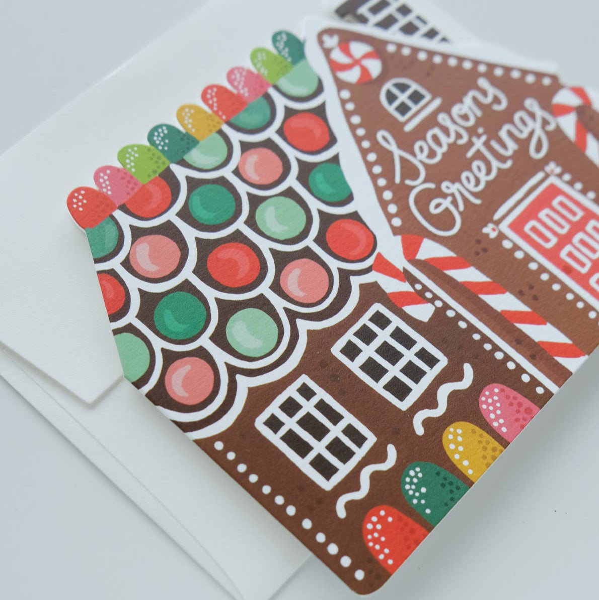 Gingerbread house-themed greeting card with 'Season's Greetings' text on a white background