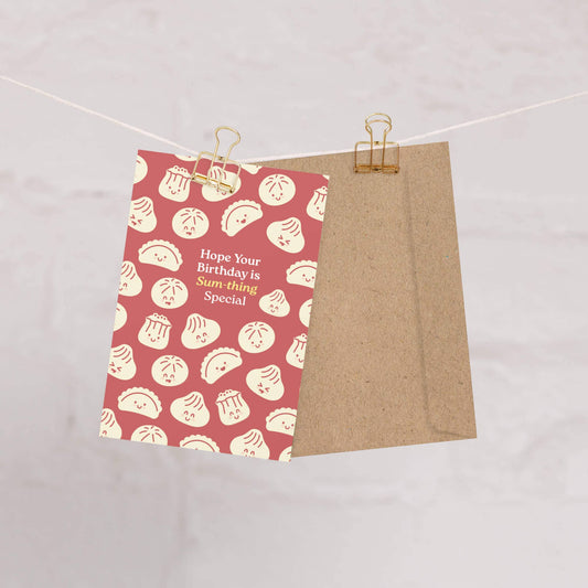 Greeting card with dumpling pattern and birthday message on a string with clips.