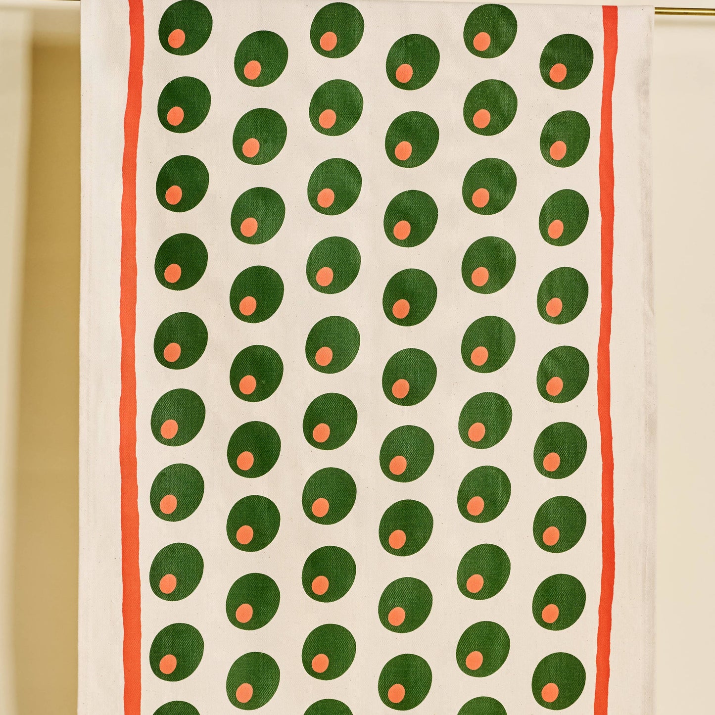 Tea towel with pimento stuffed green olives pattern on a white background with a red line border along edges