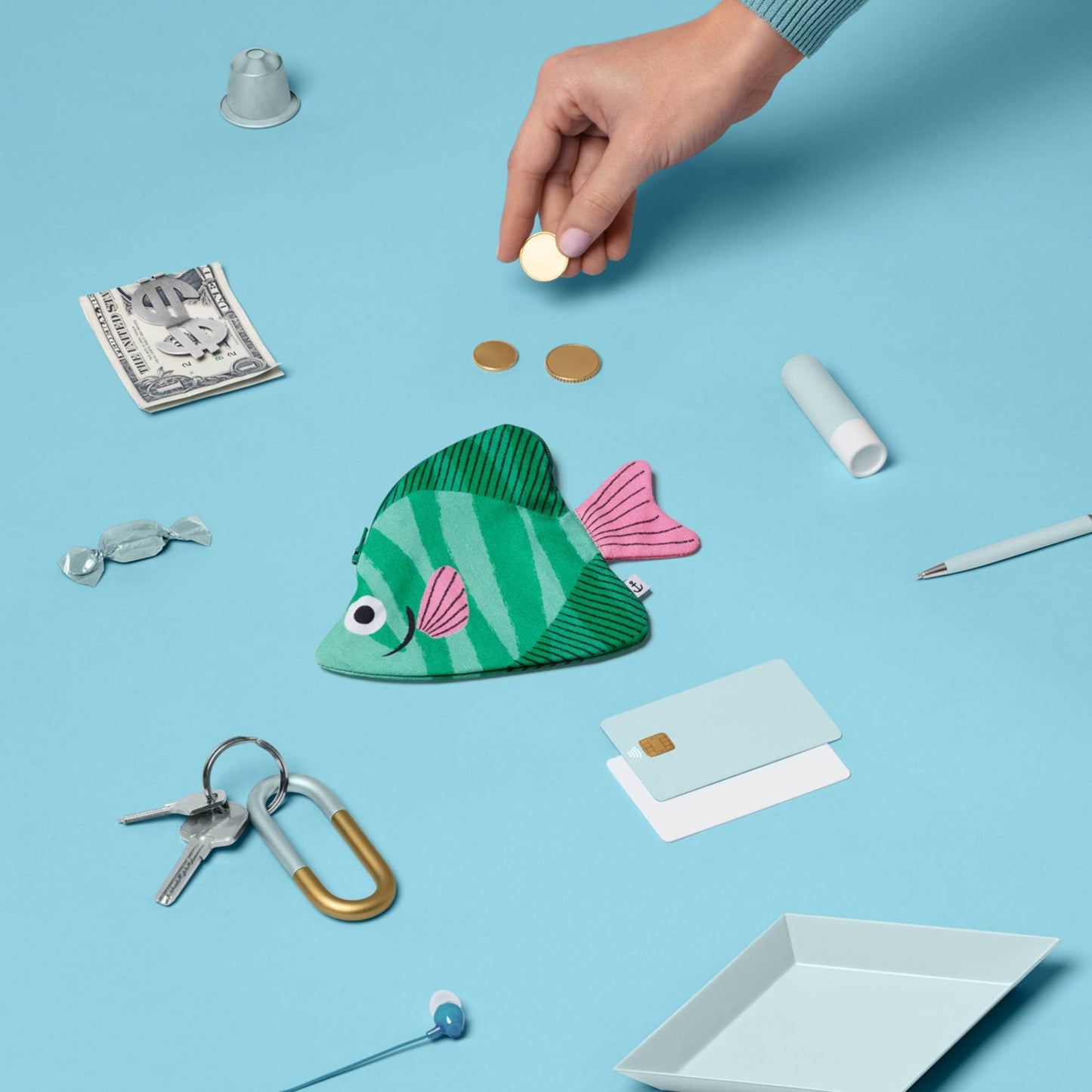 Colorful fish-shaped oouch on a blue background with coins and keys.
