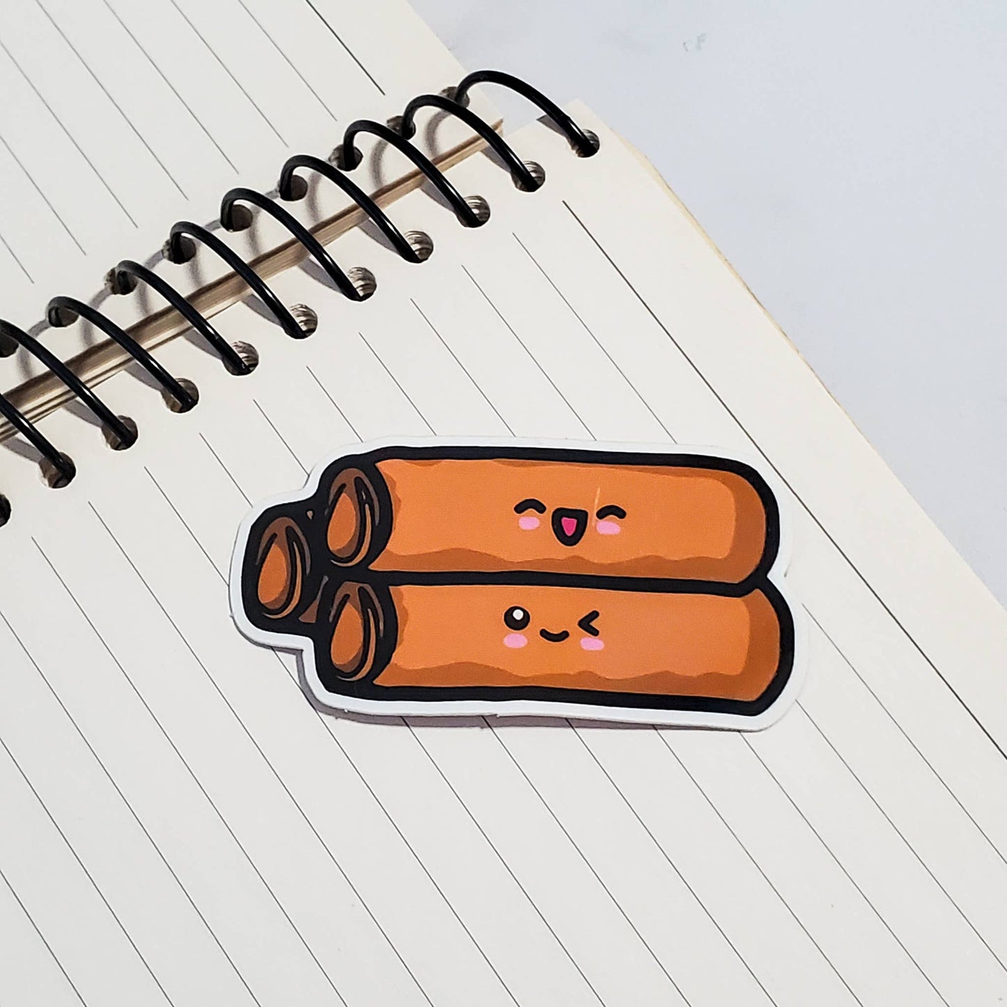 Sticker of cartoon egg rolls with faces on a notebook page