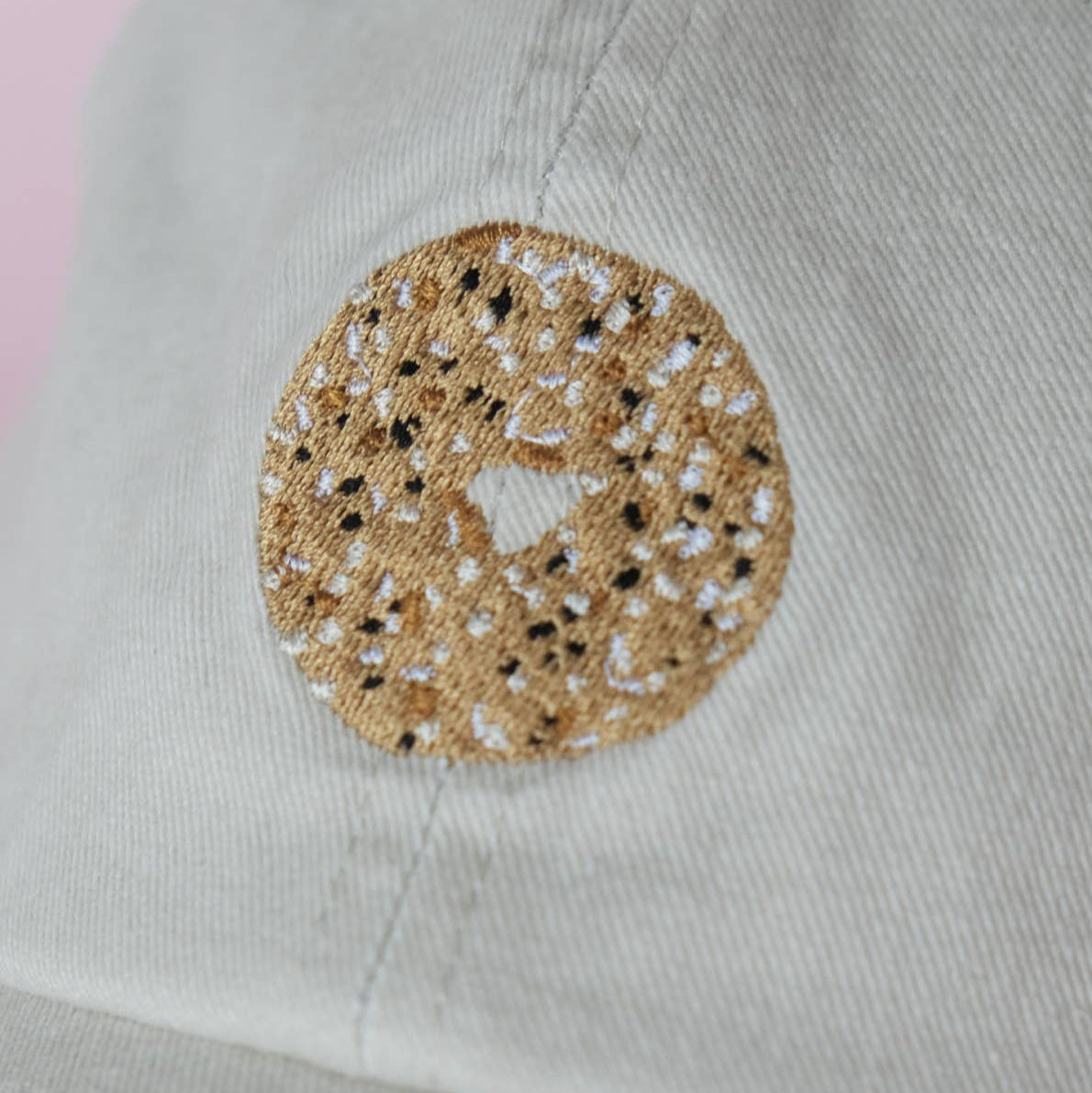 Close-up of khaki hat with a decorative embroidered everything bagel design