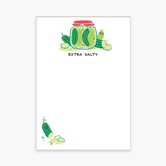 Notepad with a jar of pickles up top and a sliced one in the bottom left corner. Text up top reads "extra salty"