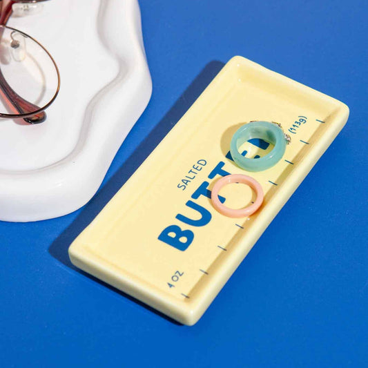 Rectangular salted butter-shaped trinket tray with colorful design on a blue surface