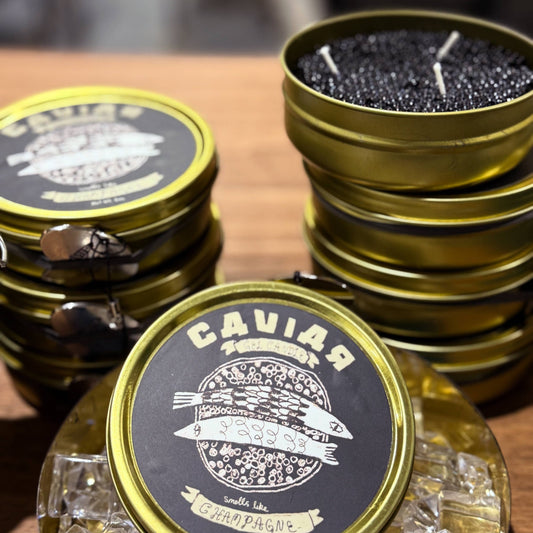 Gold and black caviar containers holding a caviar candle on a wooden surface.