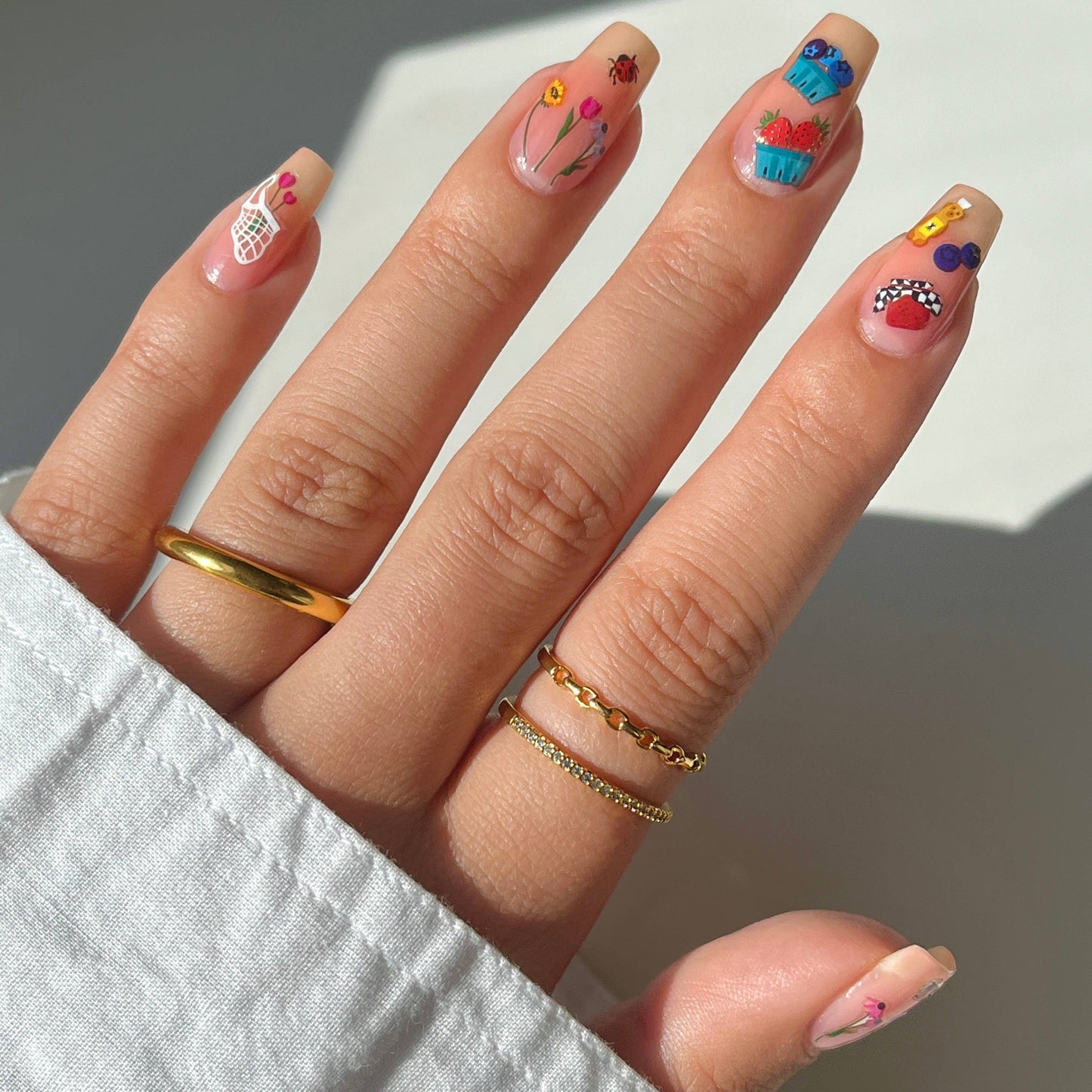 Close-up of a hand with colorful nail art on a neutral background
