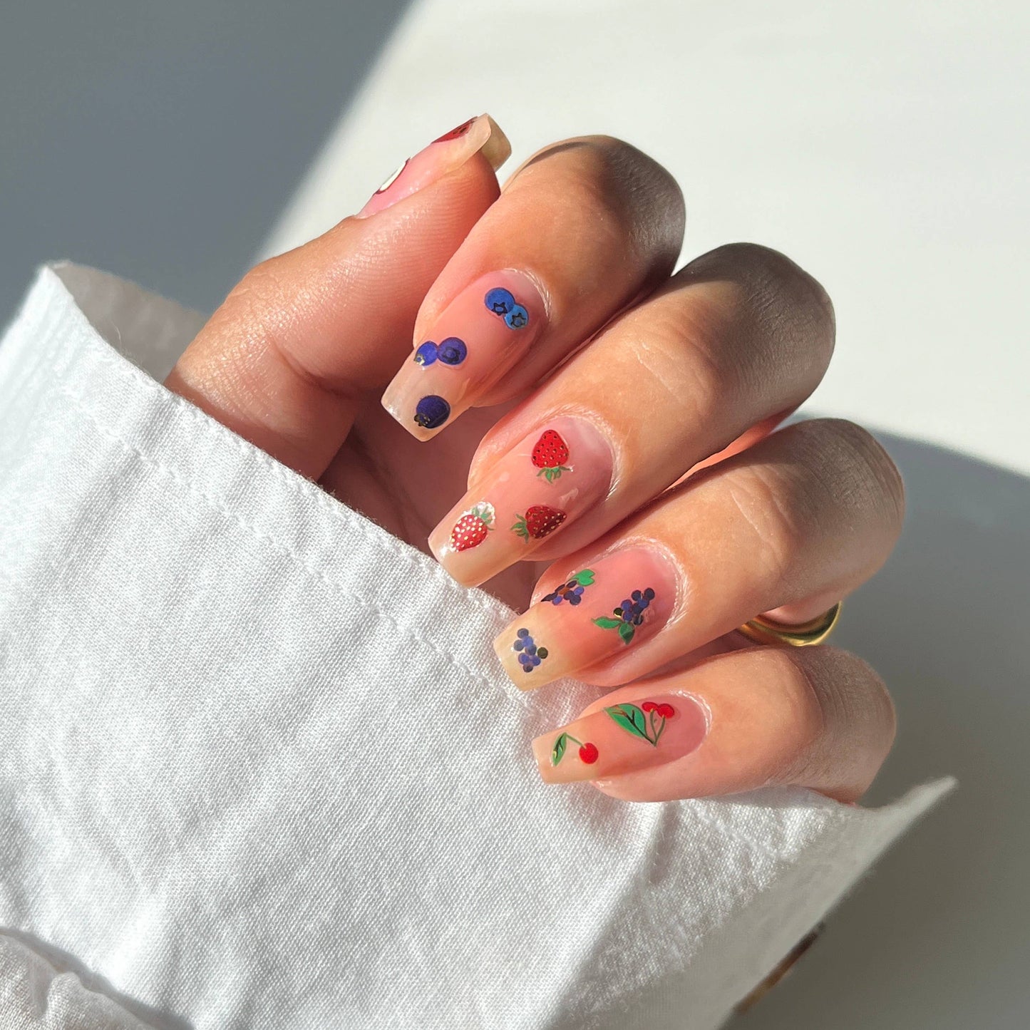Close-up of a hand with colorful nail art on a white background