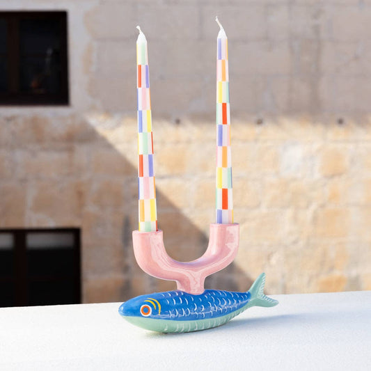 Candle holder shaped like a fish with colorful candles on a neutral background