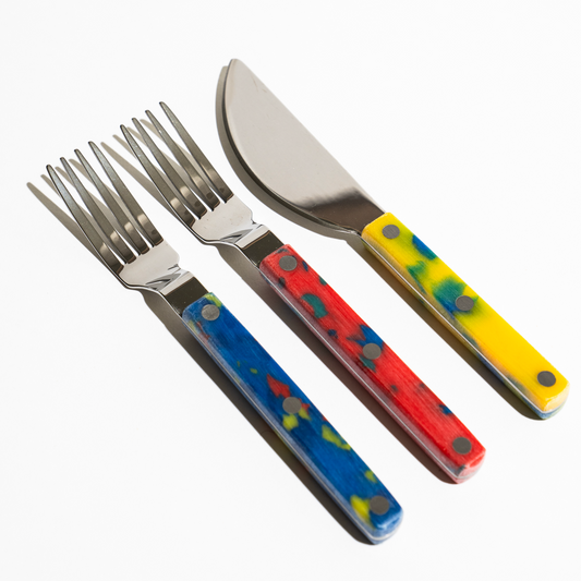 Tinned fish fork and knife set outside of box packaging -- two forks (red & blue) and one knife (yellow)
