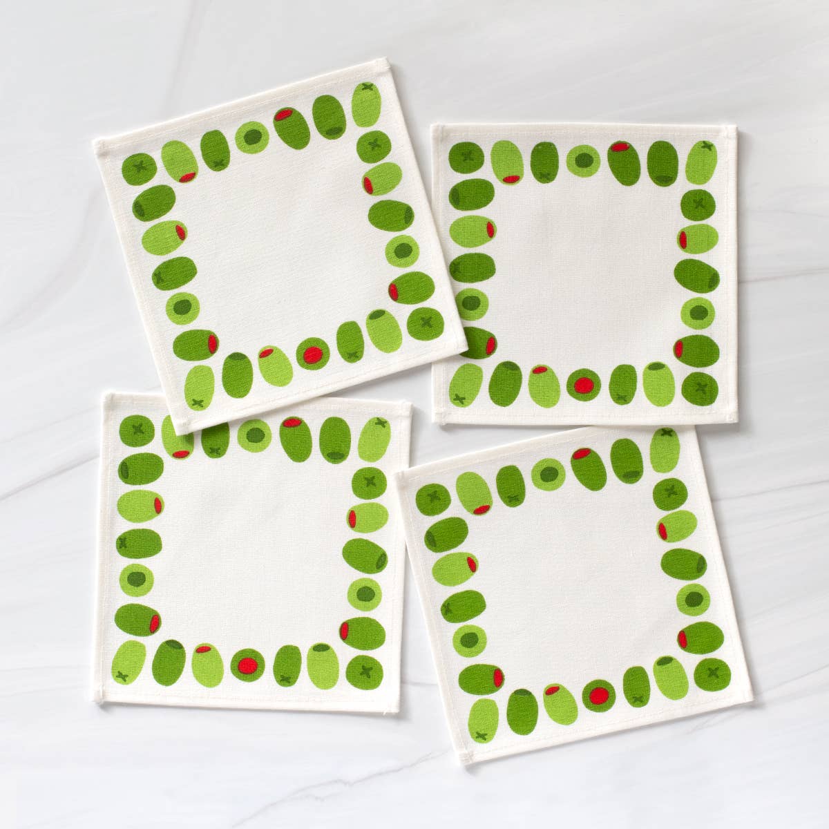 Four square cloth cocktail napkins with green stuffed olive design on a white background