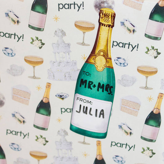 Champagne bottle gift tag sticker with 'Mr & Mrs' and 'Julia' text on a champagne themed gift wrap background.