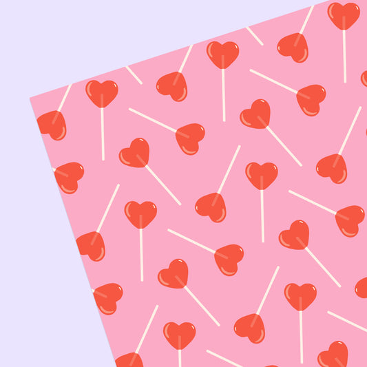sheet of pink gift wrap with red, heart-shaped lollipops all over