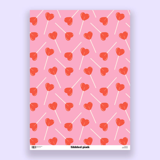 sheet of pink gift wrap with red, heart-shaped lollipops all over