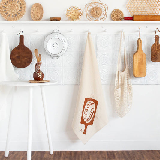 kitchen towel designed with a loaf of bread on a bread board hanging on a peg